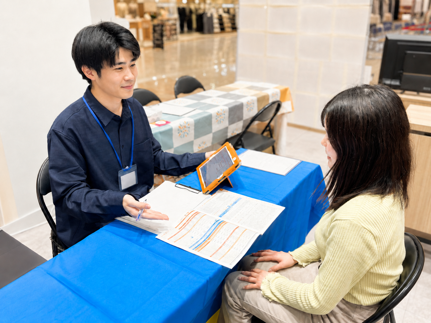 商業施設内のイベントブースでお客様に説明するField Salesスタッフ